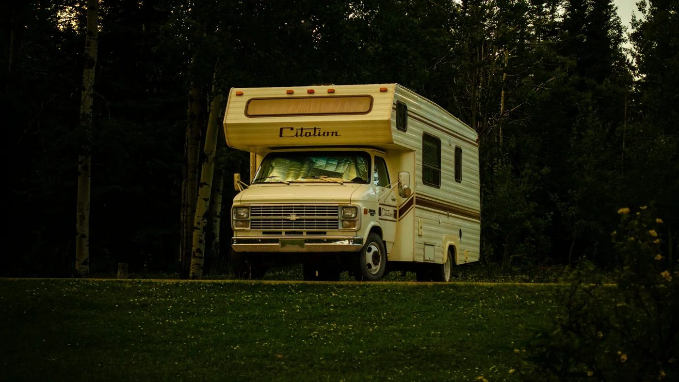 A vintage motorhome parked in a quiet forest clearing